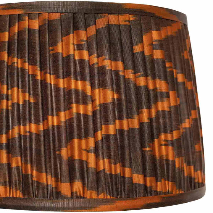 Close-up of Mekhann's silk lampshade with a brown and orange ikat design, highlighting the intricate pleating and dye quality.