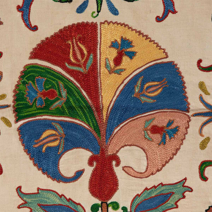 Detailed view of Mekhann's carnations petite throw, a cream throw featuring hand-embroidered carnations with colourful accents.