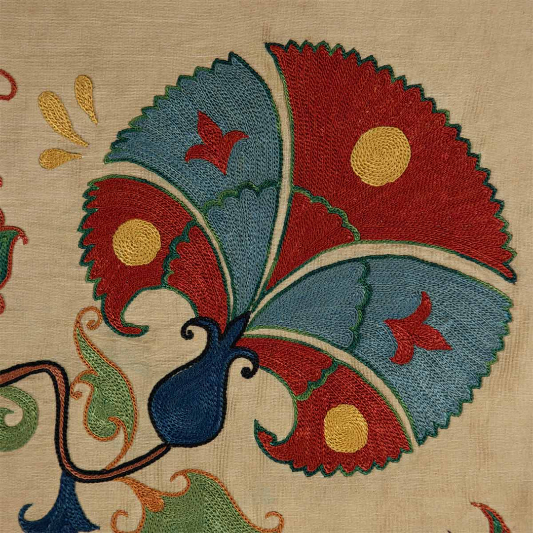 Detailed view of Mekhann's carnations petite throw, a cream throw featuring hand-embroidered carnations with colourful accents that has been embroidered onto a cream silk base.