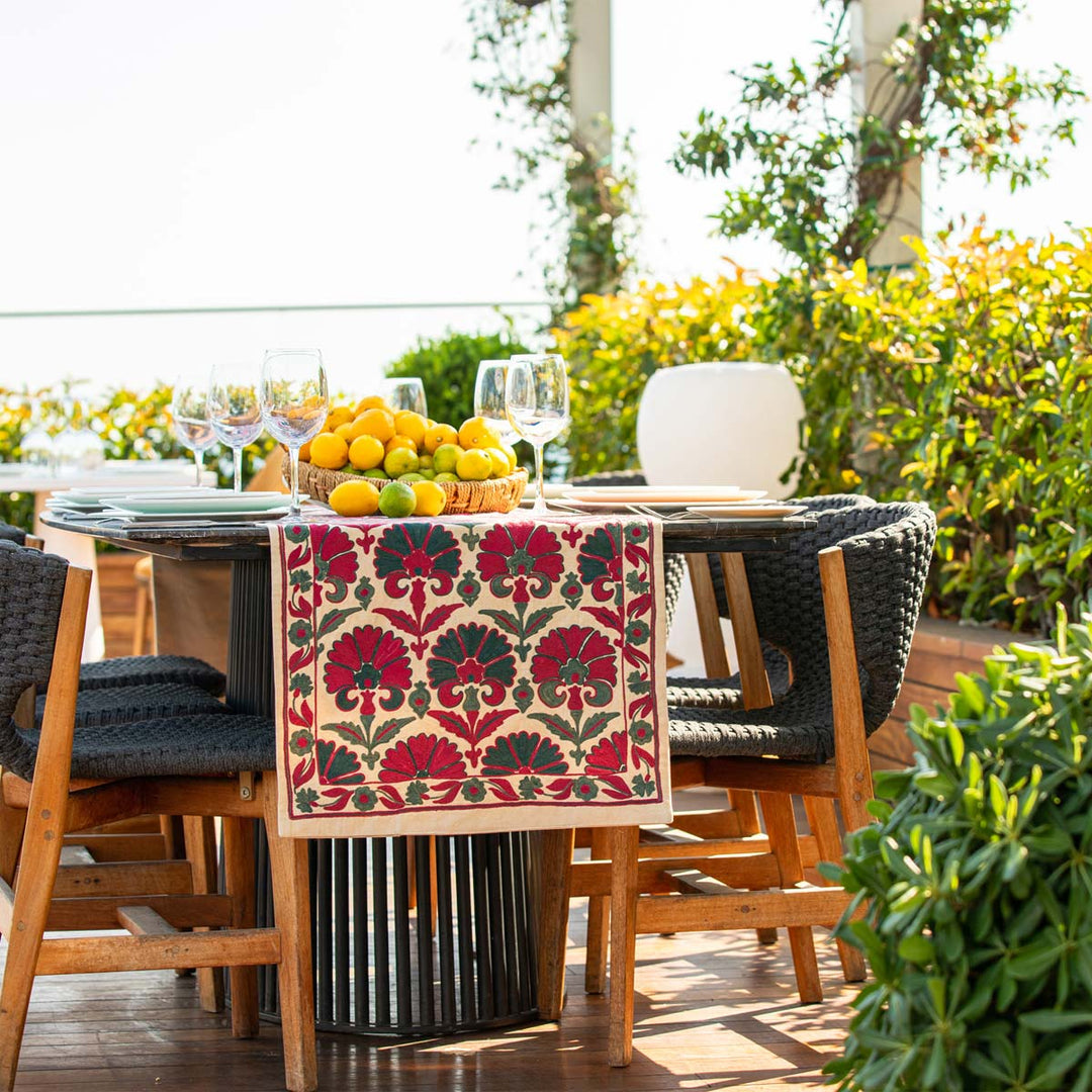 In use view of Mekhann's carnations runner in pink and teal, showing Mekhann's carnations runner outside trapped over a table, showing the different places the runner can be used.