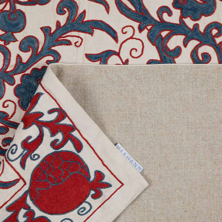 Folded view of Mekhann's cream carnations tree throw, revealing the back lining of the carnations tree throwing how the silk looks next to it for colour referencing.