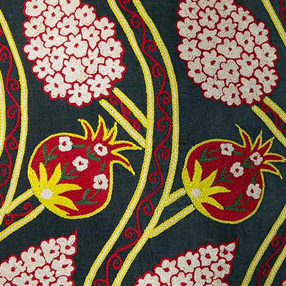 Close up view of Mekhann's black grapes and pomegranates embroidered cushion, showcasing the attention to detail in the stitching of the pomegranate and grape motifs that have been had embroidered using silk.
