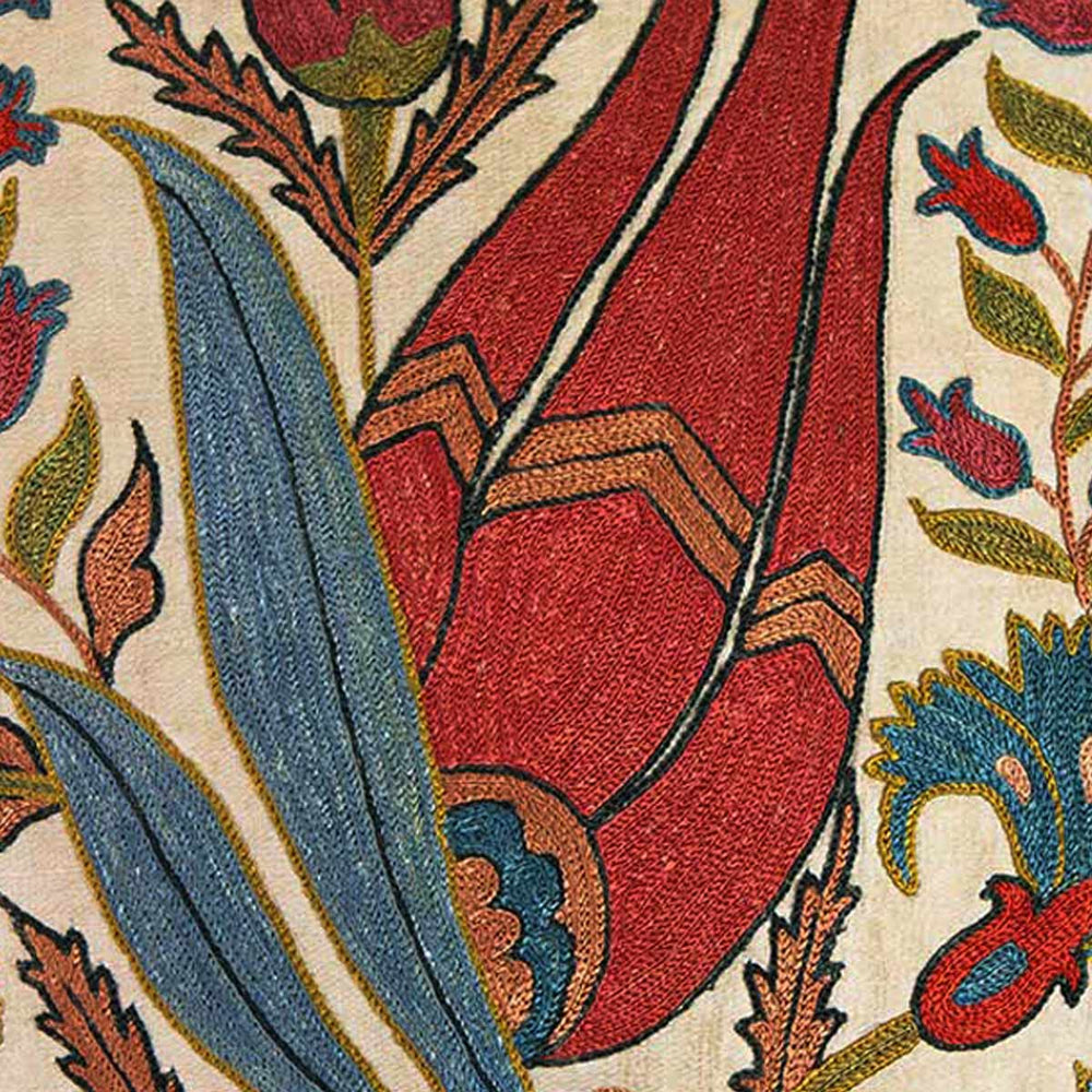 Close up view of Mekhann's cream tulips embroidered cushion, displaying the details and texture of the bright red tulip motifs and the black silk yarns that have been embroidered to outline it.