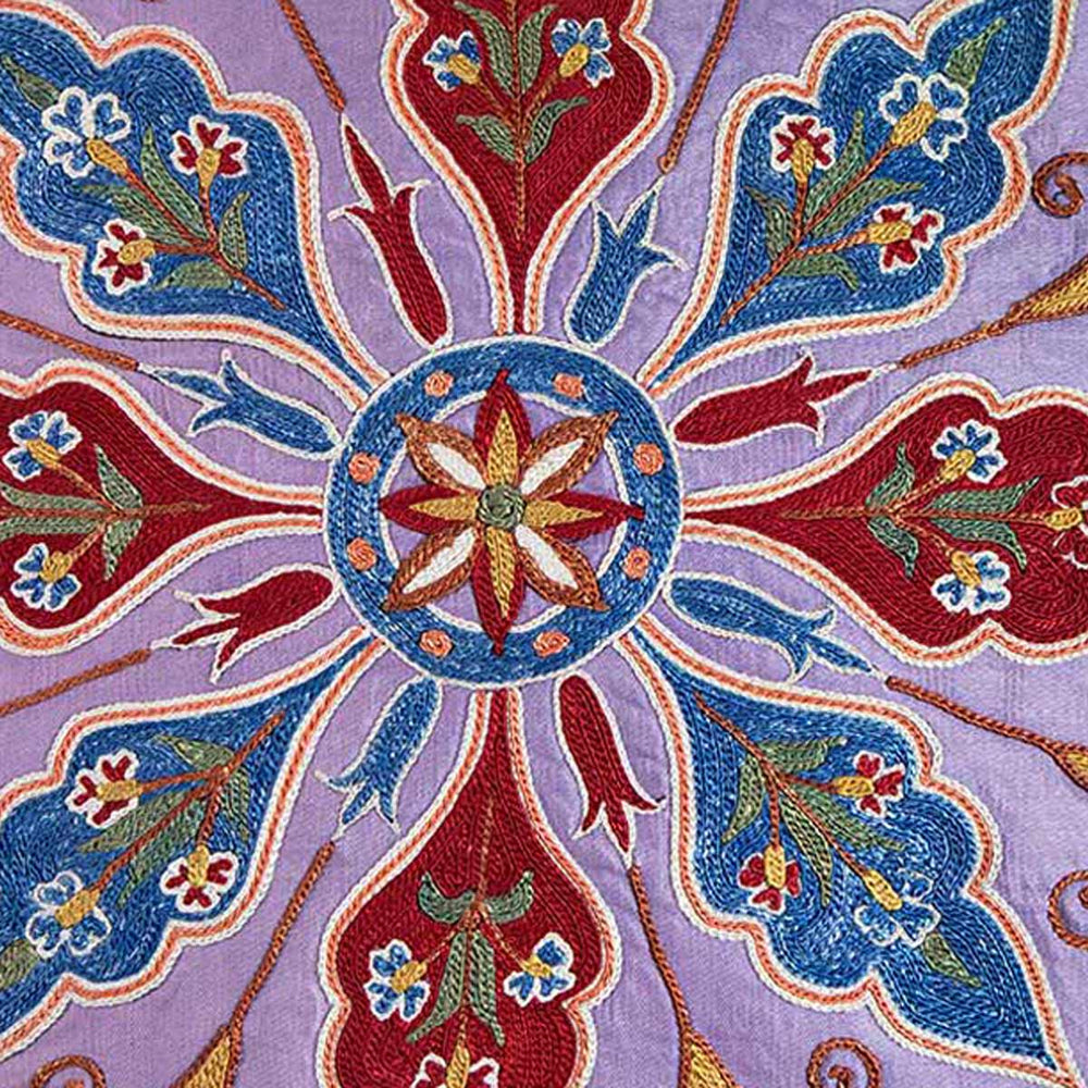 Close up view of Mekhann's multicoloured abstract embroidered cushion, with red and blue hand embroidered detailing on a purple silk canvas.