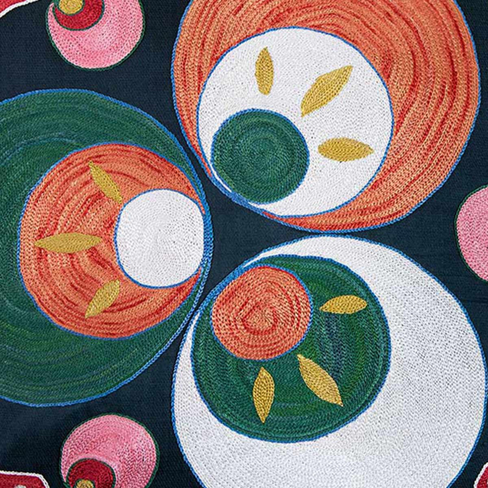 Close up view of Mekhann's black and green Cintamani embroidered cushion, here we can see the detailed embroidery of the Cintamani patterns that have been created using green, cream and orange silk yarns.