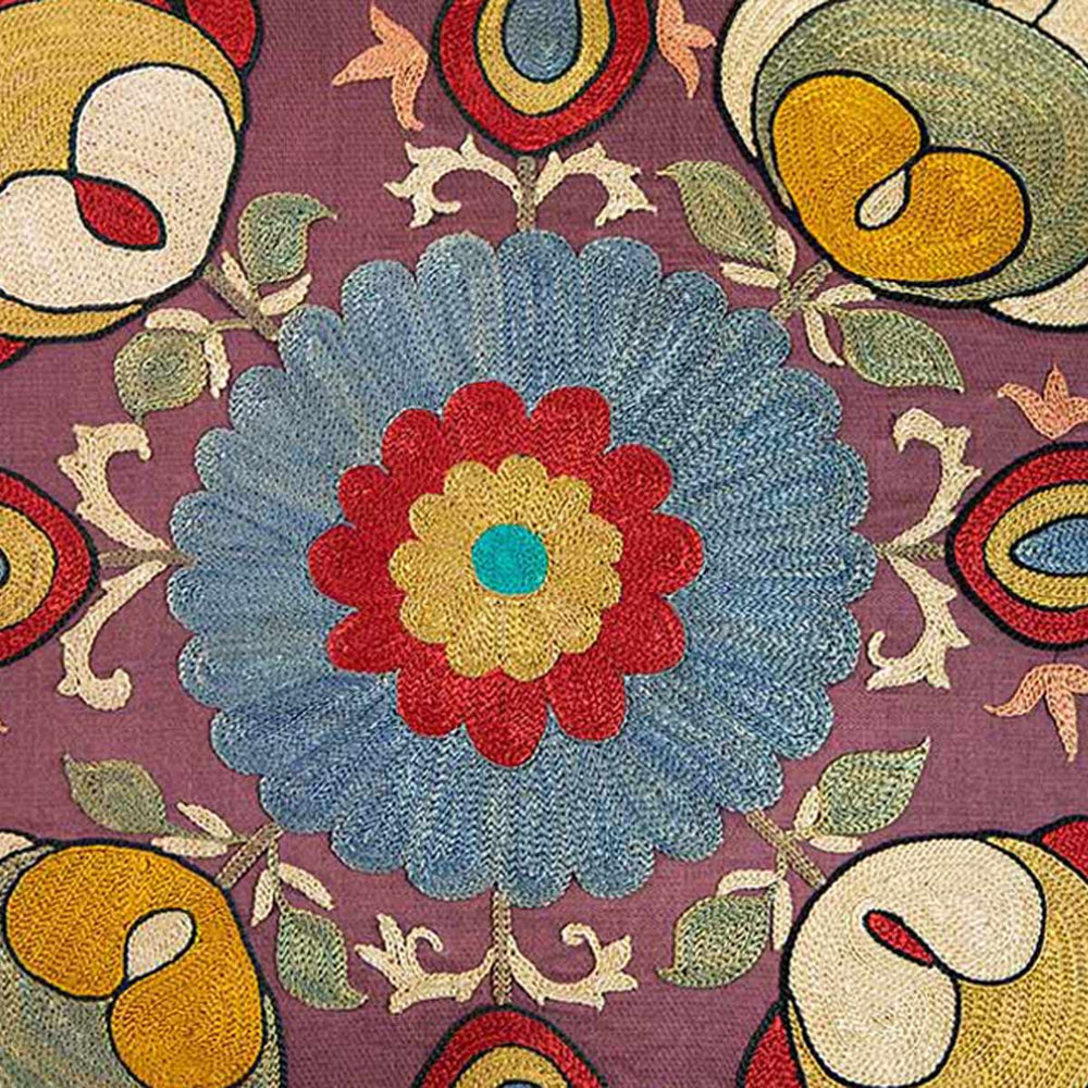 Close up view of Mekhann's multicoloured lotus embroidered cushion, Revealing the central flower motif of the cushion that has been created using blue, red and yellow silk yarns.