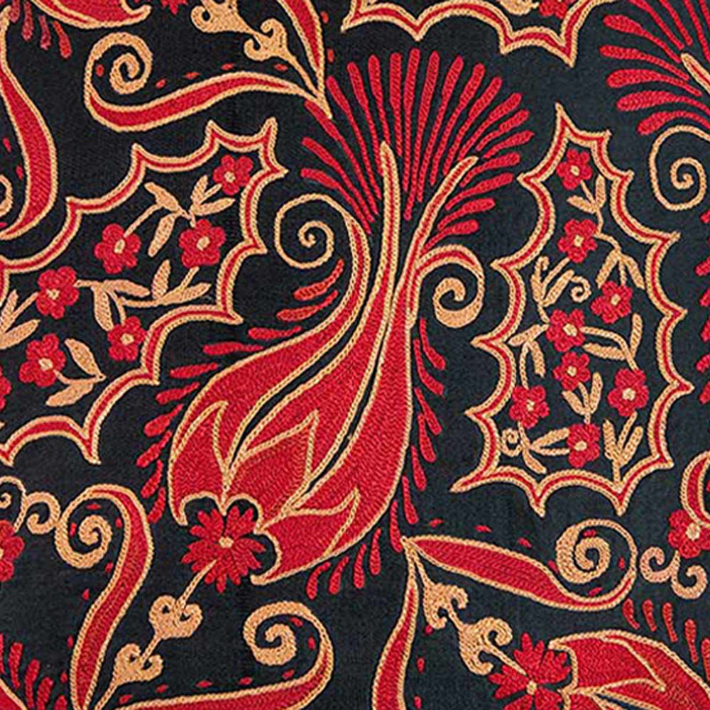 Close up view of Mekhann's red and black iznik embroidered cushion, bringing you closer to one of the red flower motifs that stand out against the black silk backdrop.