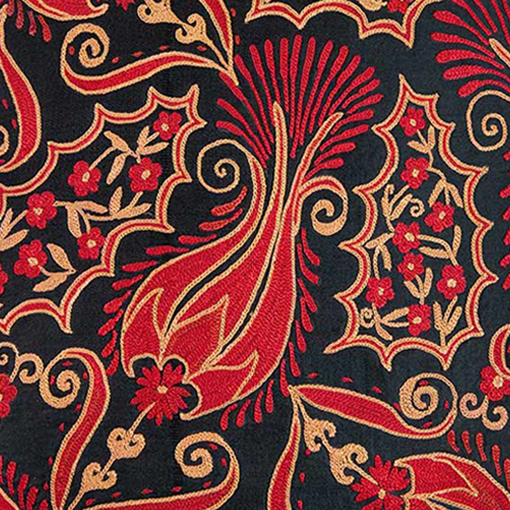 Close up view of Mekhann's red and black iznik embroidered cushion, bringing you closer to one of the red flower motifs that stand out against the black silk backdrop.