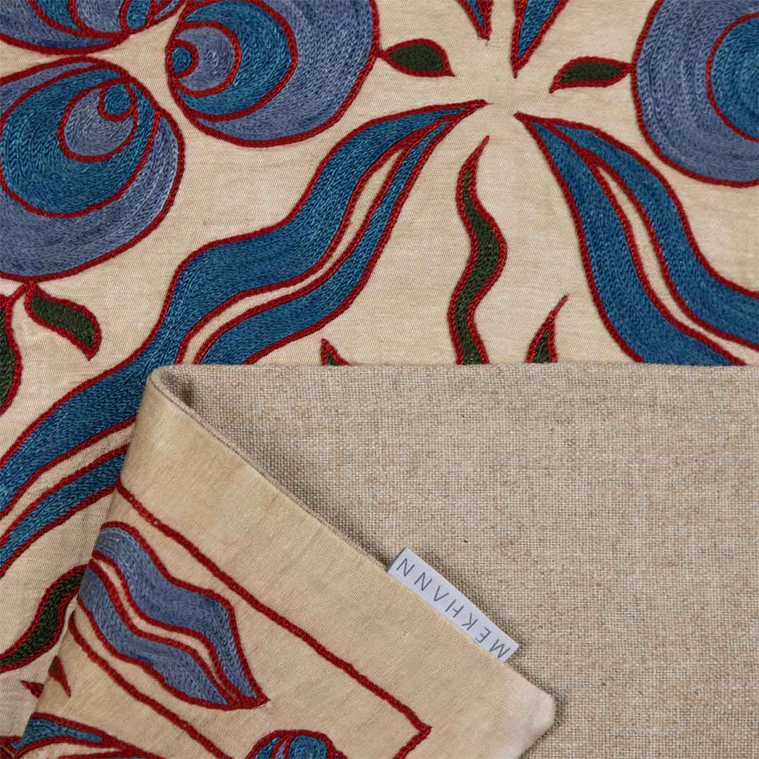 Folded view of Mekhann's cream cintamani runner, showing all of the hand embroidered details on the cintamani patterns, and revealing the lining of the back of the runner.