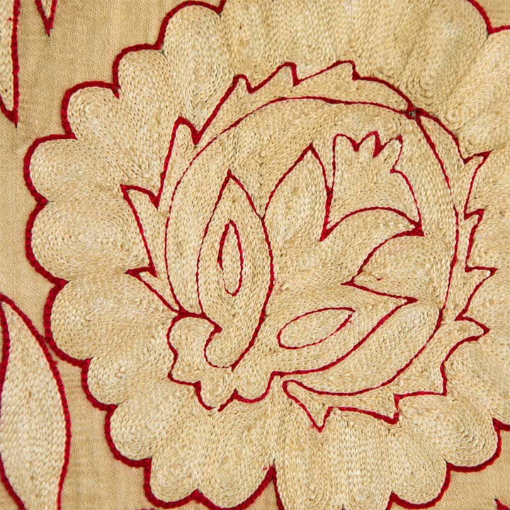 Detailed view of Mekhann's cream botanical throw, showing how the red thread details contrast with the like cream embroidered, working together to make up this beautiful floral design motif.