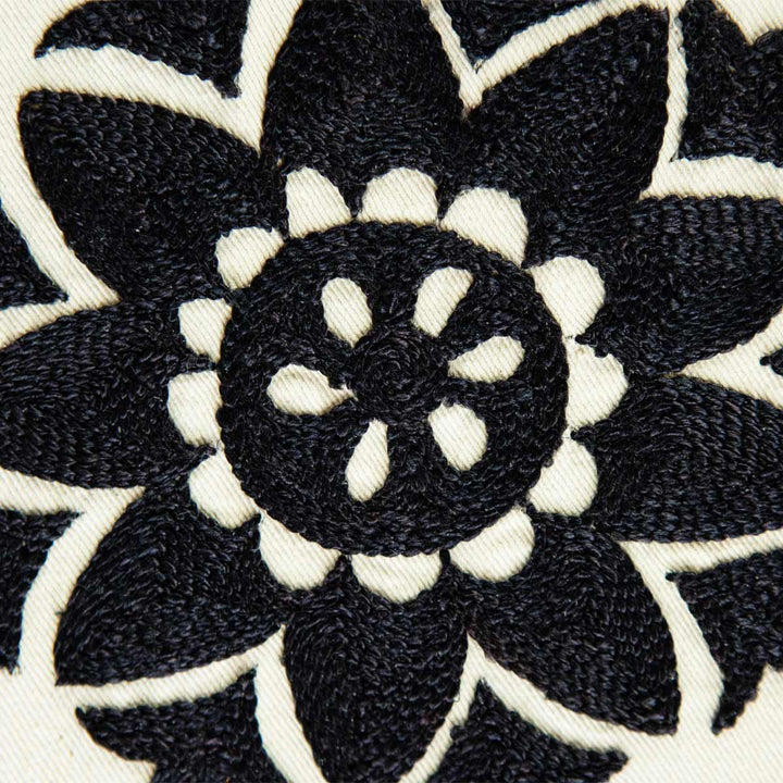 Detailed view of Mekhann's white and black silk artwork with organic botanical hand embroidered shapes. showcasing a black embroidered flower on white silk, we can see the attention to detail in every stitch.