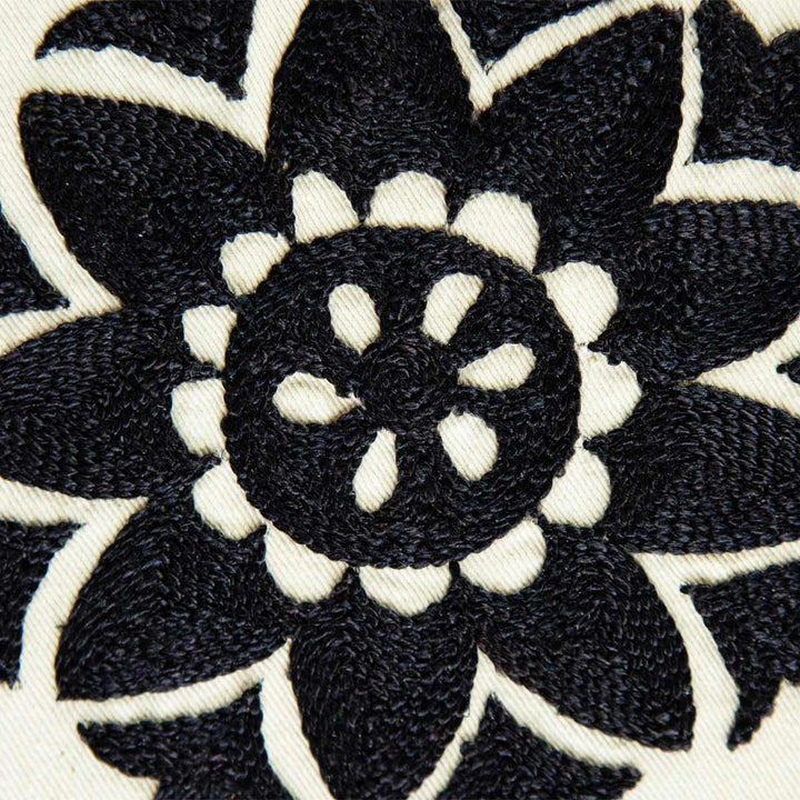 Detailed view of Mekhann's white and black silk artwork with organic botanical hand embroidered shapes. showcasing a black embroidered flower on white silk, we can see the attention to detail in every stitch. 