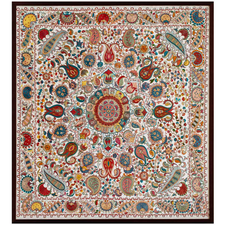 Front view of cream silk, multicoloured embroidered framed artwork, revealing a full composition of bright embroidered colours all on a base of cream silk. The patterns are natural in shape all centred around the middle medallion. All of this within a dark walnut frame.