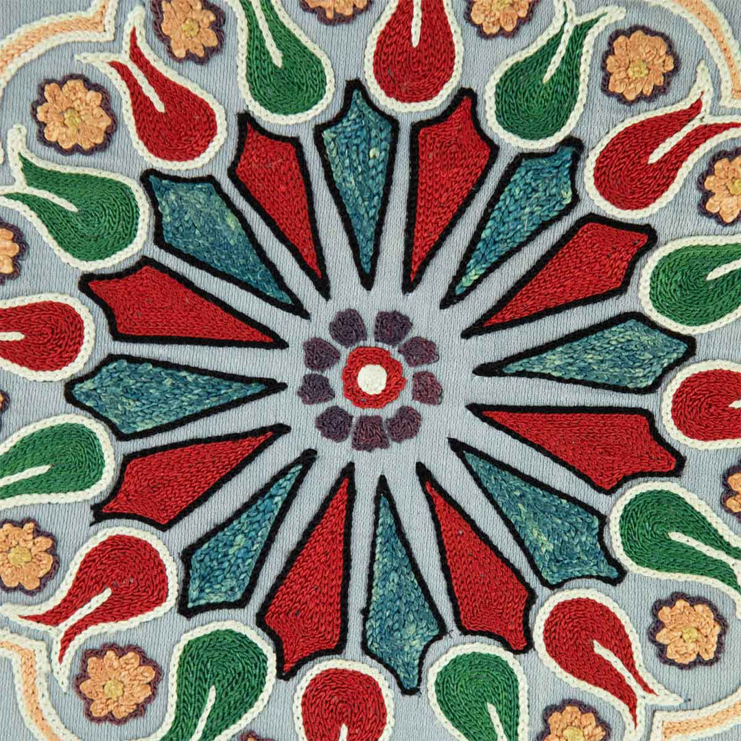 Close up view of Mekhann's grey silk carnations artwork, a detailed view of the medallion like centre mortis with tones of vibrant red, blue, green, and light yellow. All design motifs have been hand embroidered.