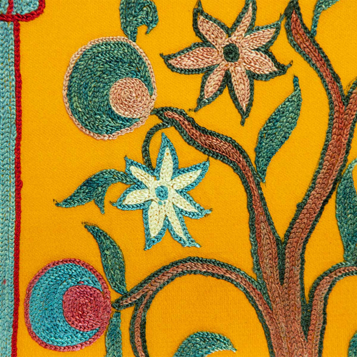 Close up view of Mekhann's yellow silk garden artwork, with the branches in embroidered silk with a teal outline, all hand embroidered onto yellow silk.