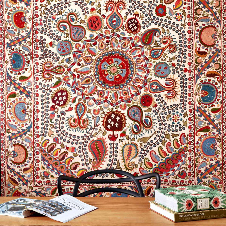 In use view of Mekhann's cream and multicoloured silk artwork with a collection of hand embroidered patterns. Showcasing the silk embroidered artwork behind a desk, giving the viewer possible ideas of usage.