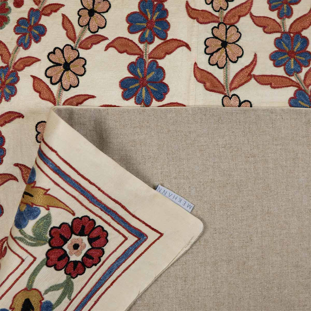 Folded view of Mekhann's cream iznik throw, where the back lining is revealed with the mekhann label in shot.