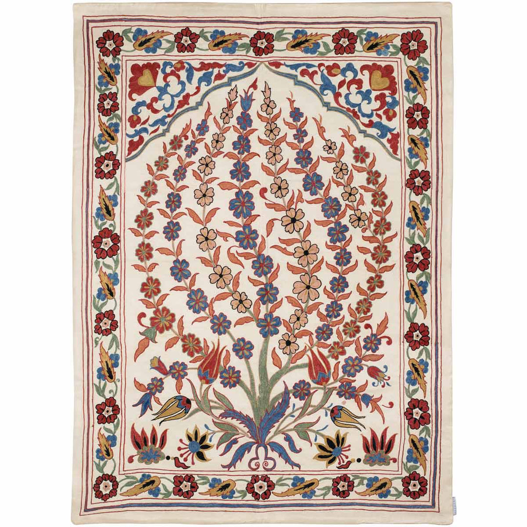 Front view of Mekhann's cream iznik throw, where we can see a full collection of flowers, vines and other classic iznik design Motifs, that have come together to create the composition of this iznik throw. All design elements have been hand embroidered onto a cream silk background .