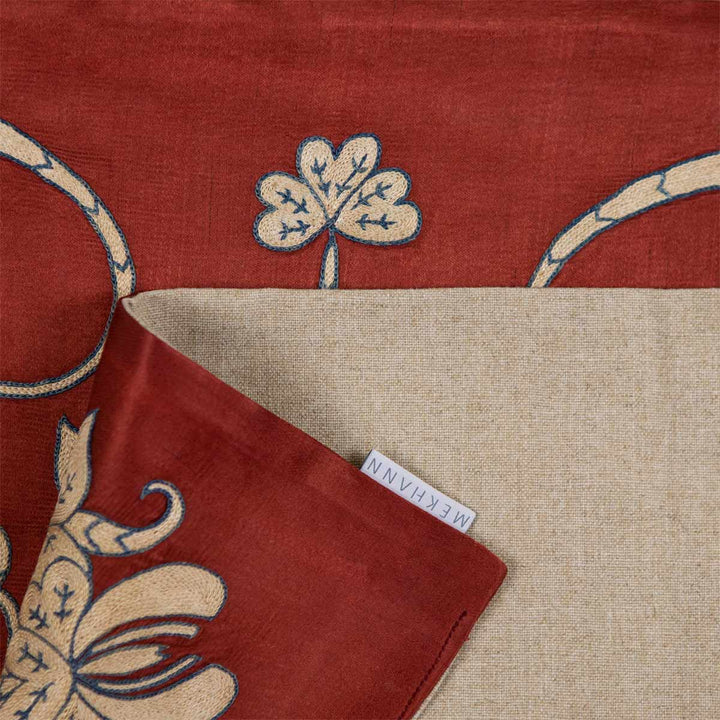 Folded view of Mekhann's maroon baroque petite throw, showcasing the back lining alongside the Mekhann label.