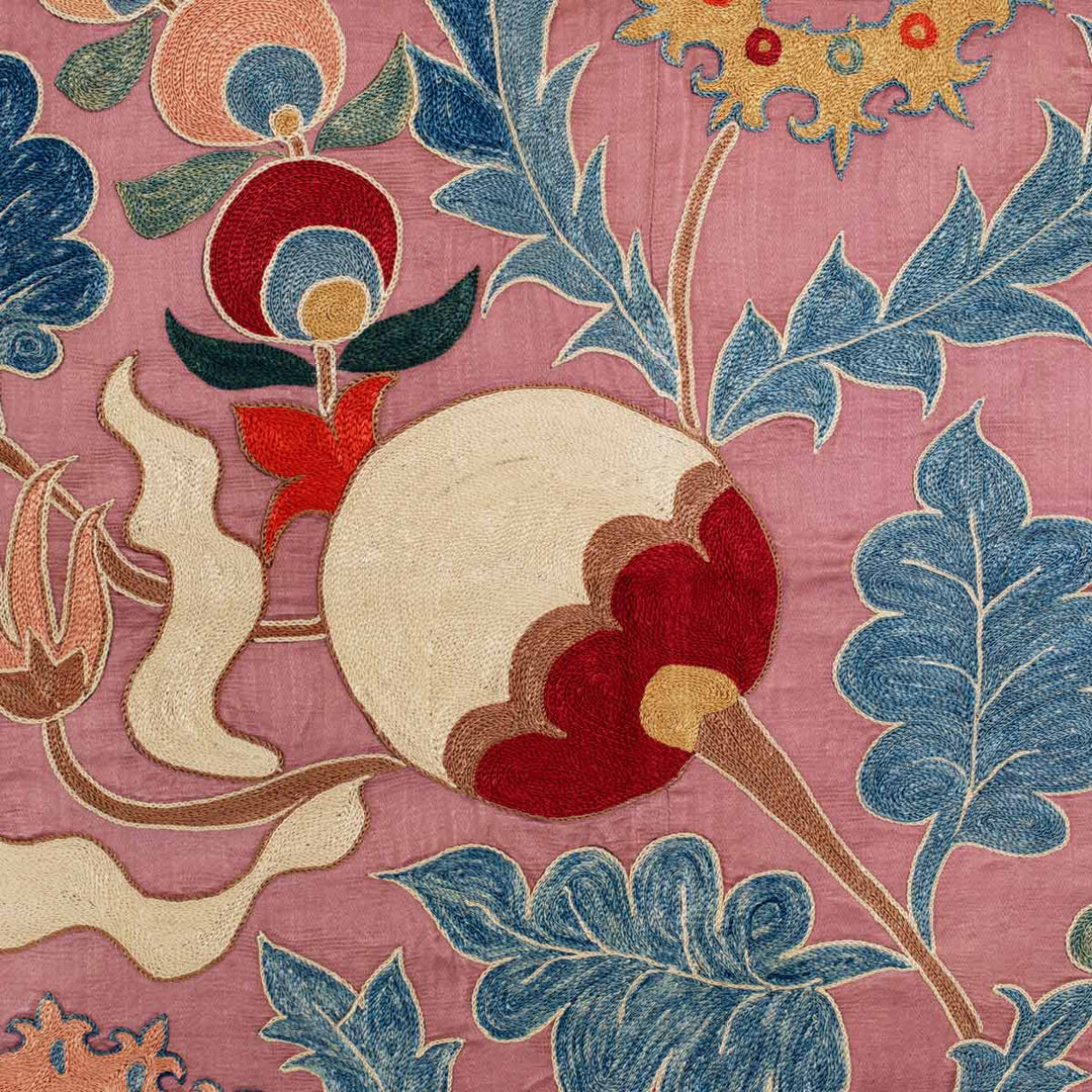 Close up view of Mekhann's violet iznik throw, showcasing the attention to detail of the hand embroidered patterns and how the contrast with the smooth texture of the violet silk back drop.