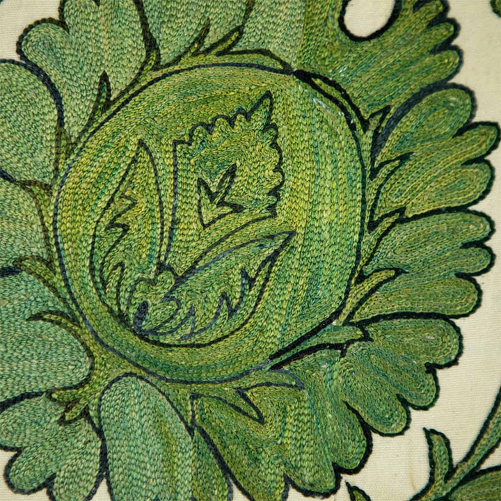 Close up view of Mekhann's emerald botanical throw, showcasing the extreme attention to detail of the direction of the hand embroidered silk threads and how they make up this botanical motif in green.