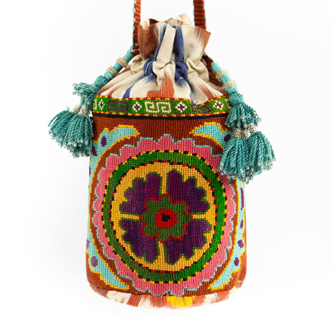 Front view of Mekhann's multicoloured floral embroidered bucket bag, showcasing it's blue tassels and bold design. 