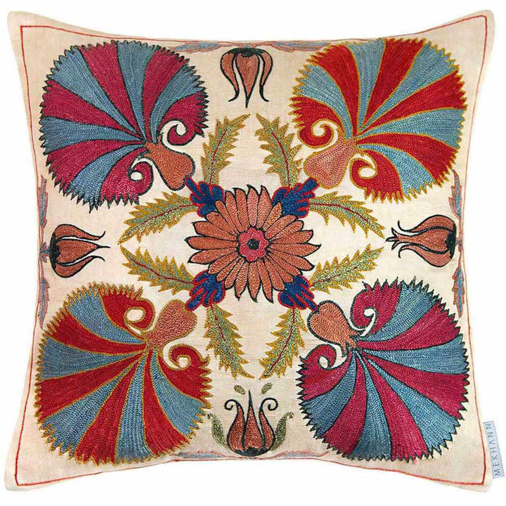 Front view of Mekhann's cream carnations embroidered cushion, showcasing four large carnations designs all hand embroidered in red, pink and shades of blue. It is also surrounded by other organic matter like leaves and flowers, all of which have been hand embroidered. 