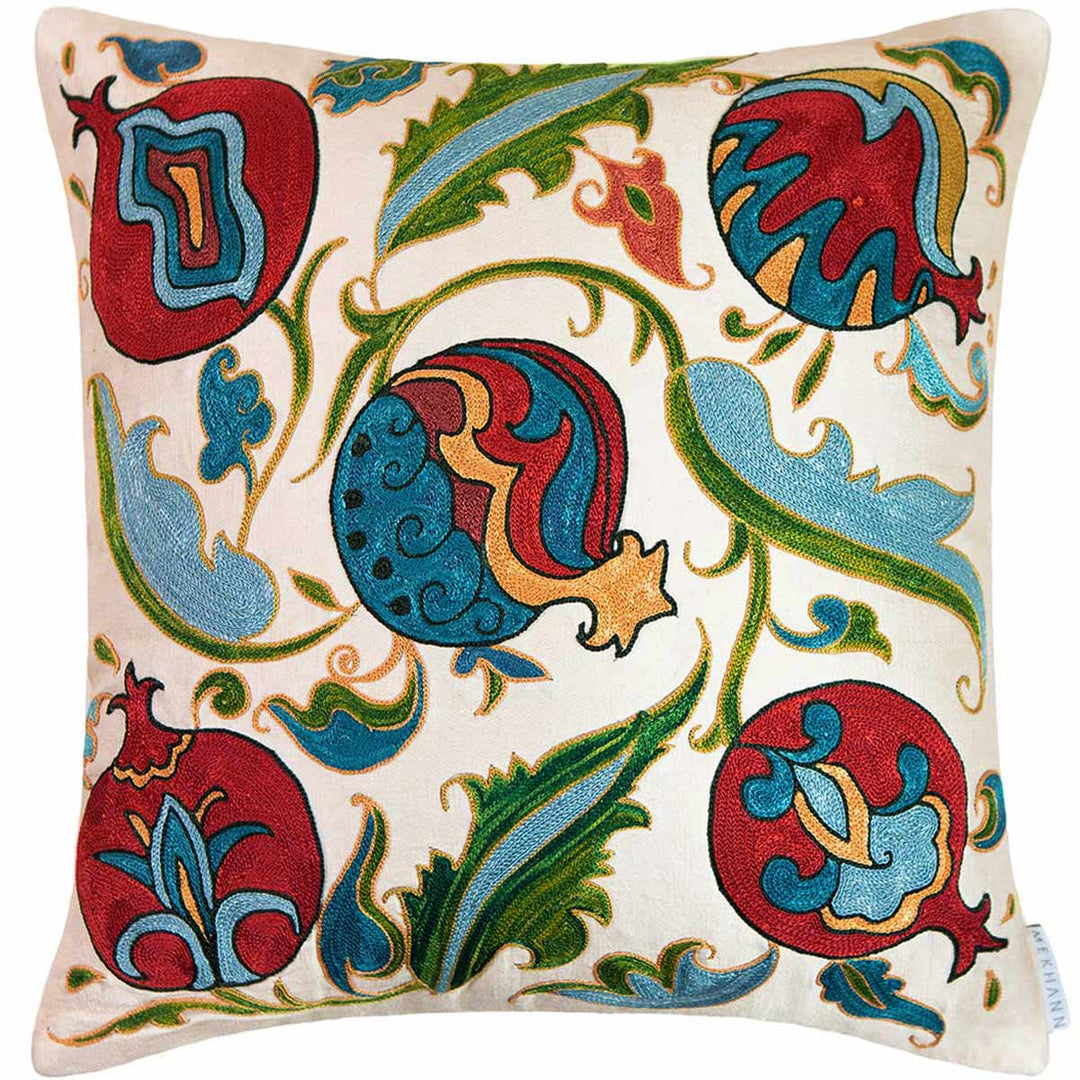 Front view of Mekhann's cream pomegranate hand embroidered cushion, here can can see the five pomegranate embroidered motifs in a collection of red, blue, green and light yellow hues.