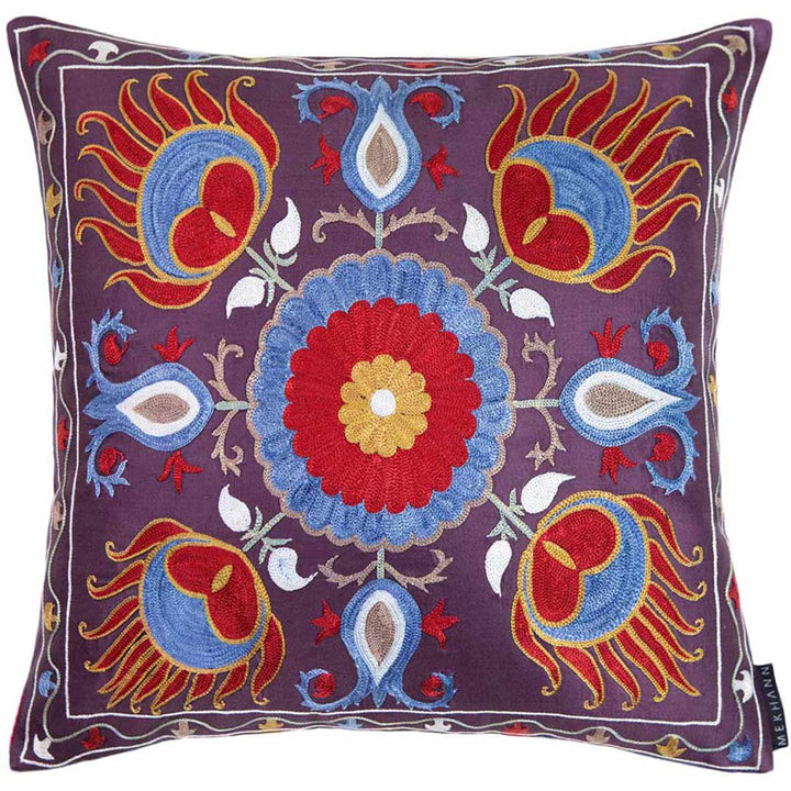 Front view of Mekhann's multicoloured lotus embroidered cushion, showing a colourful composition of red, blue and cream embroidery all on a base of dark purple.