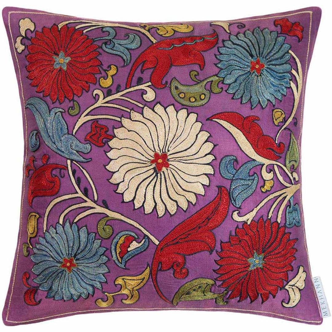 Front view of Mekhann's pink sunflower embroidered cushion, showcasing a collection of blue, red and cream sunflowers surrounded by leaves and other organic matter.