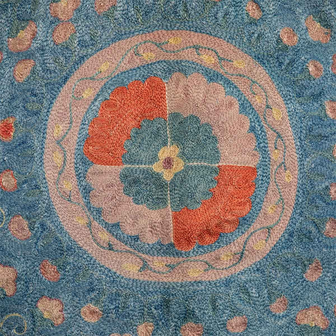 Detailed view of Mekhann's fully embroidered lividus II kaftan in navy, displaying a medallion motif in soft lilac and soft red to create a muted and delicate design.