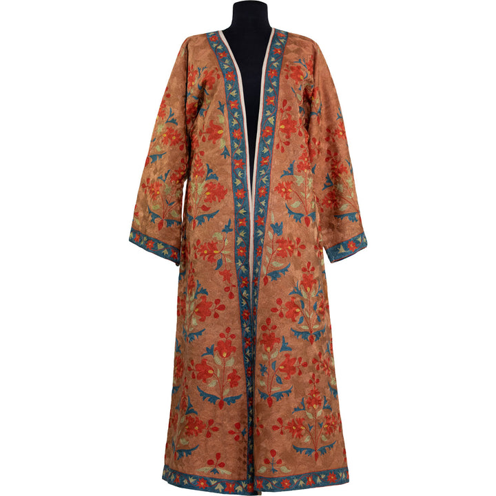 Front view of Mekhann's fully embroidered aurantius kaftan in orange, with full embroidery detailing, showcasing the intricate pattern and elegant trim. Showcasing tones of orange, blue and reds