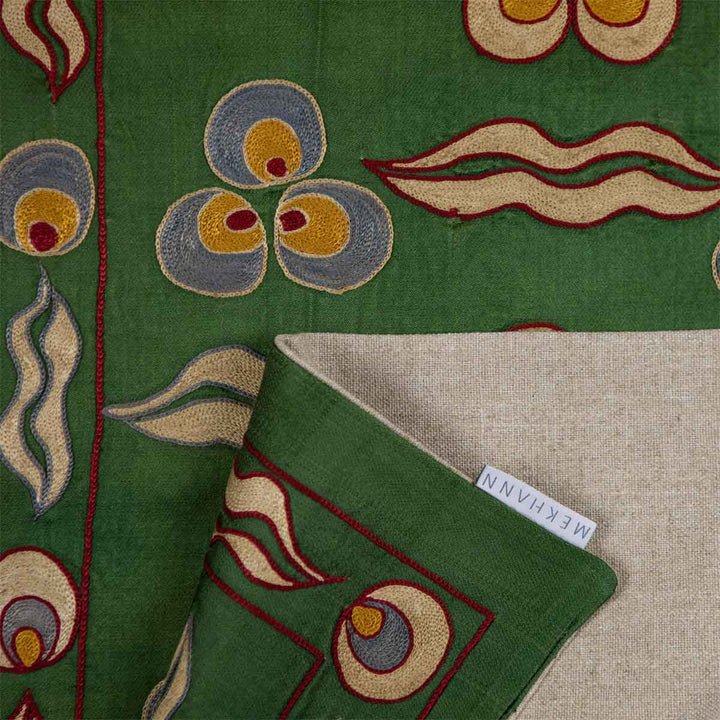 Folded view of Mekhann's green cintamani runner, showing all of the hand embroidered details of the cintamani pattern, also revealing the durable back lining of the runner.