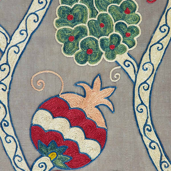 Close up view of Mekhann's grey silk hand embroidered vines artwork, showing one of the pomegranate and vines motifs, all hand embroidered in naturally dyed silk against a grey silk base.