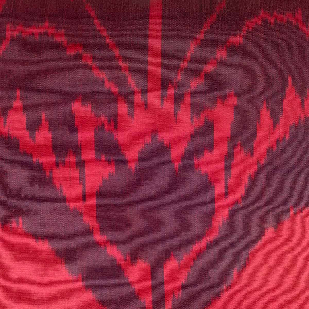 Close-up of the Carnation motif on a handwoven pure silk Ikat cushion, showcasing intricate weaving and deep red hues achieved through traditional dyeing techniques.