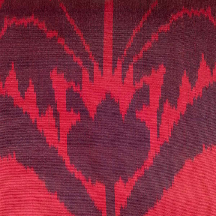 Close-up of the Carnation motif on a handwoven pure silk Ikat cushion, showcasing intricate weaving and deep red hues achieved through traditional dyeing techniques.