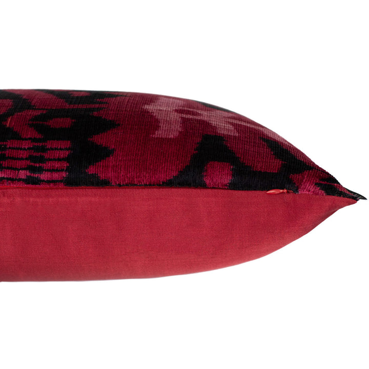 Side view of handwoven silk velvet Ikat cushion in fuchsia and black, highlighting its plush texture, intricate Sagitta pattern, and artisanal craftsmanship.
