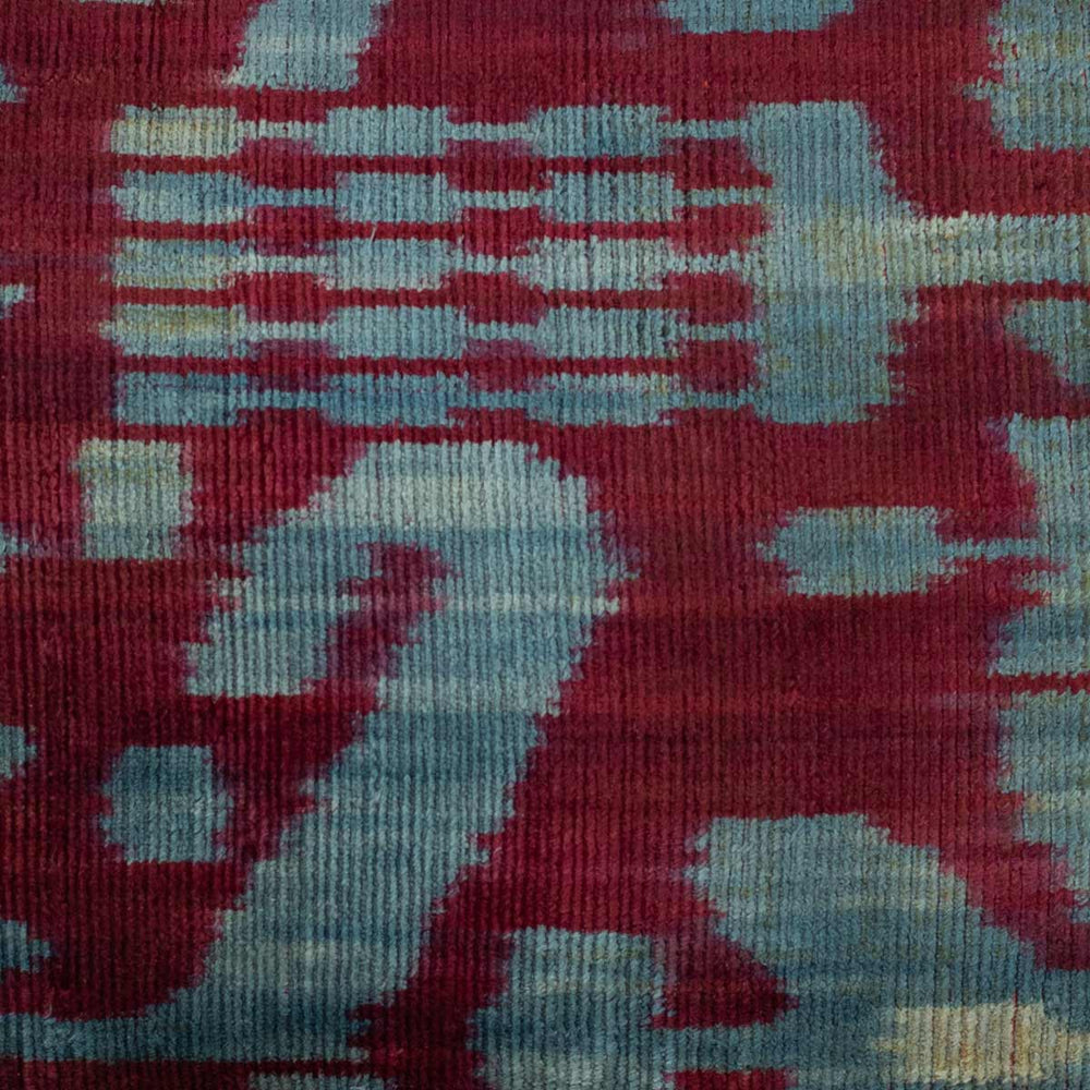Close-up of handwoven silk velvet Ikat cushion in royal purple and azure, showcasing the intricate Sagitta pattern—crafted using traditional resist-dyeing techniques for a rich, blurred-edge effect.