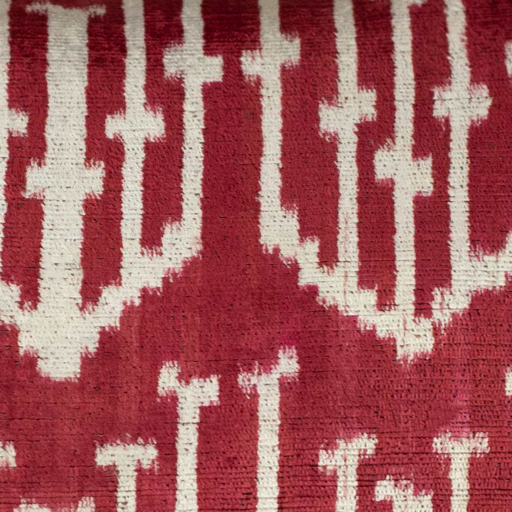 Close-up of the Spearhead motif on a handwoven silk velvet ikat cushion, highlighting the deep crimson and burgundy hues with intricate resist-dye techniques.