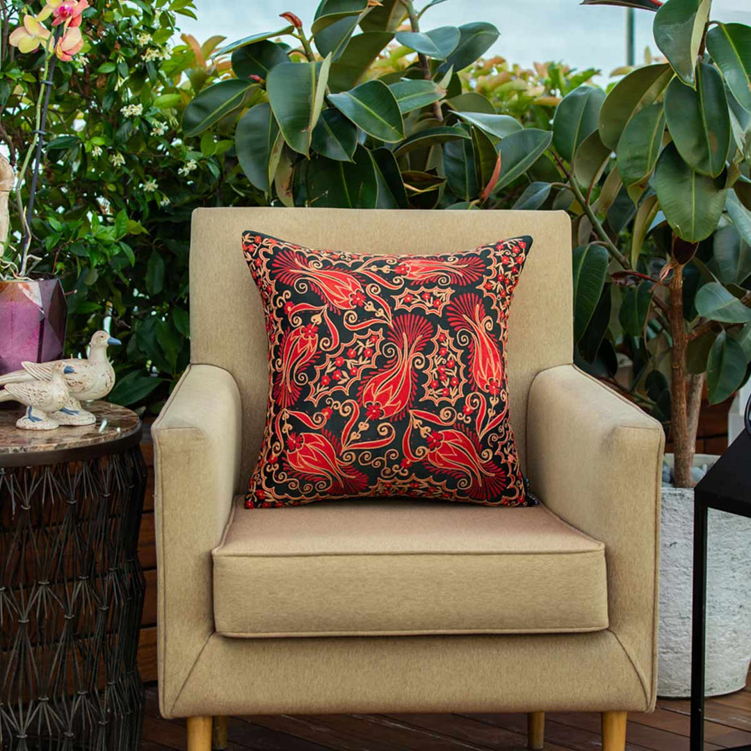 In use view of Mekhann's red and black iznik embroidered cushion, showing the hand embroidered cushion on a chair, giving an idea of how the product can be placed.