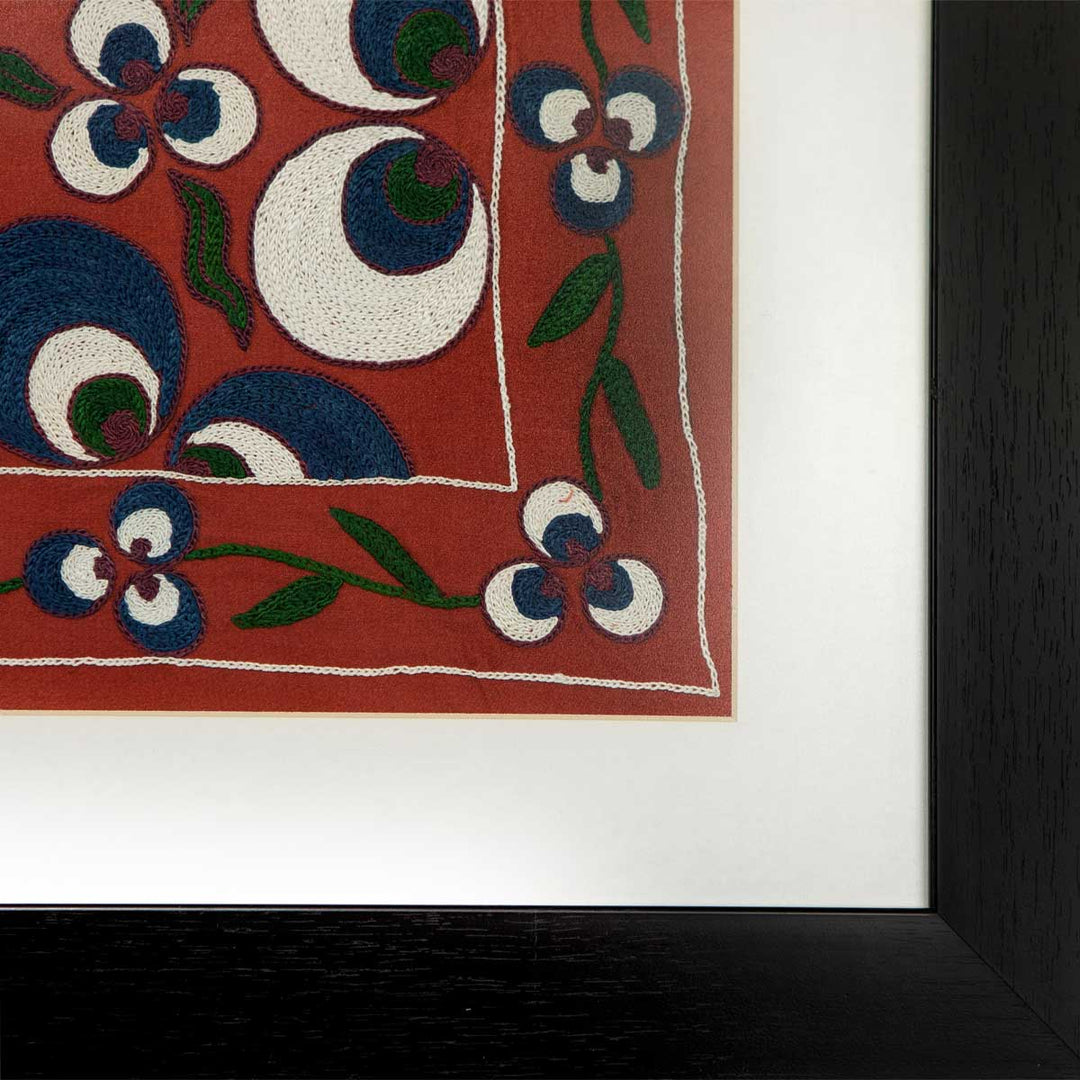 Corner view of Mekhann's maroon silk cintamani artwork, showing the white space that separates the black frame from the maroon silk framed artwork.