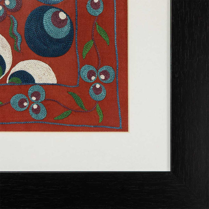 Corner view of Mekhann's light maroon silk cintamani artwork, bringing a closer view of the white space that separates the black frame from the light maroon base.