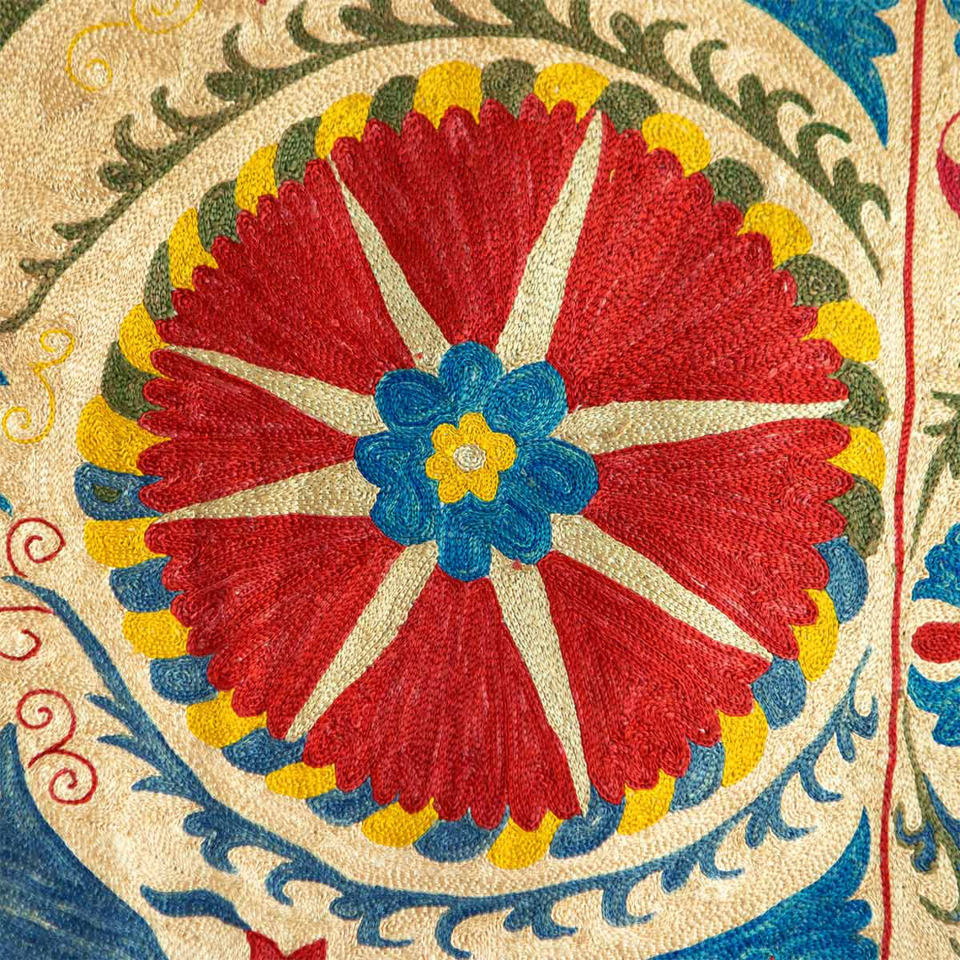 Detailed view of Mekhann's multicoloured medallion throw, showing one of the medallion motifs up close with bright red, blue, yellow and green tones. You can see all the detailed hand embroidered that has gone into creating the medallion motif.