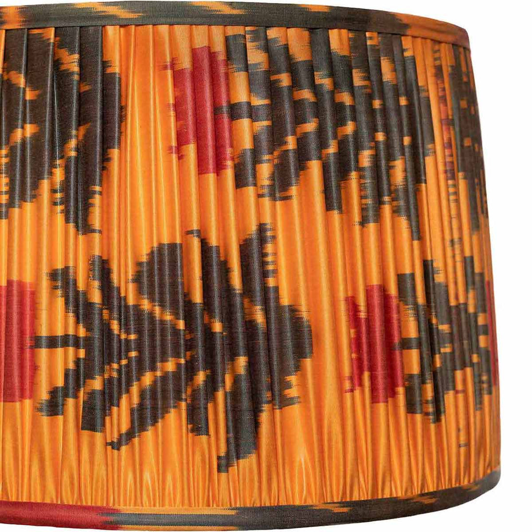 Close-up of Mekhann's orange silk lampshade with detailed black floral ikat design, exemplifying artisanal skill.