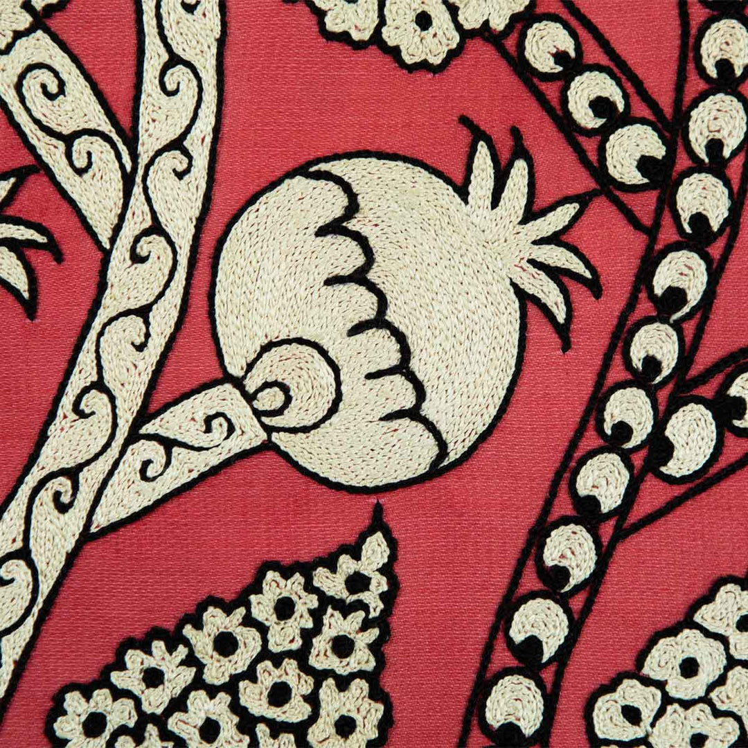 Close up view of Mekhann's hand embroidered, pink silk artwork, showing one of the cream pomegranate motifs up close, revealing the intricate embroidery techniques.
