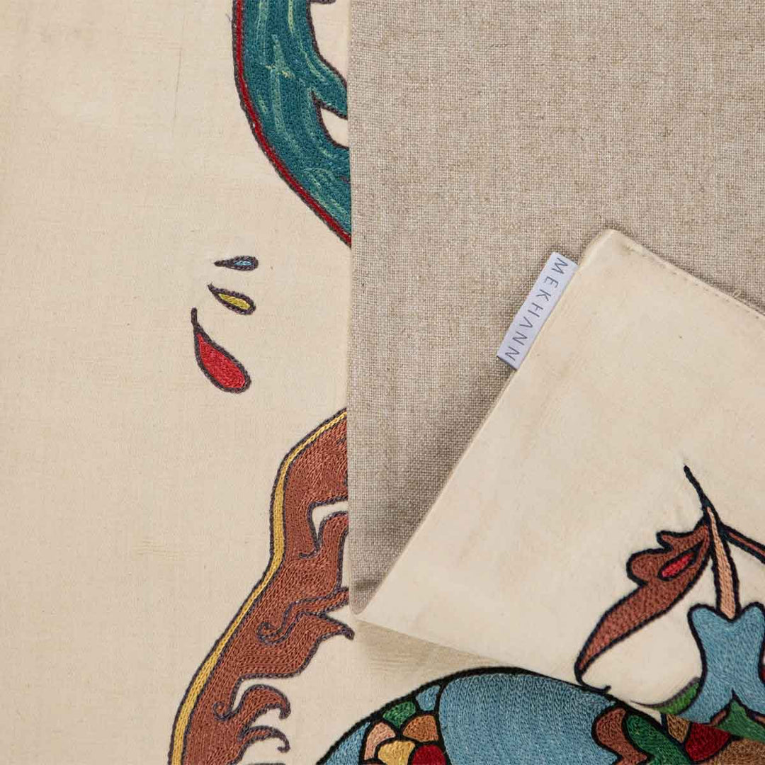 Folded view of Mekhann's pomegranate cream petite throw, showcasing the back lining alongside the Mekhann label, revenging the texture of the back lining.