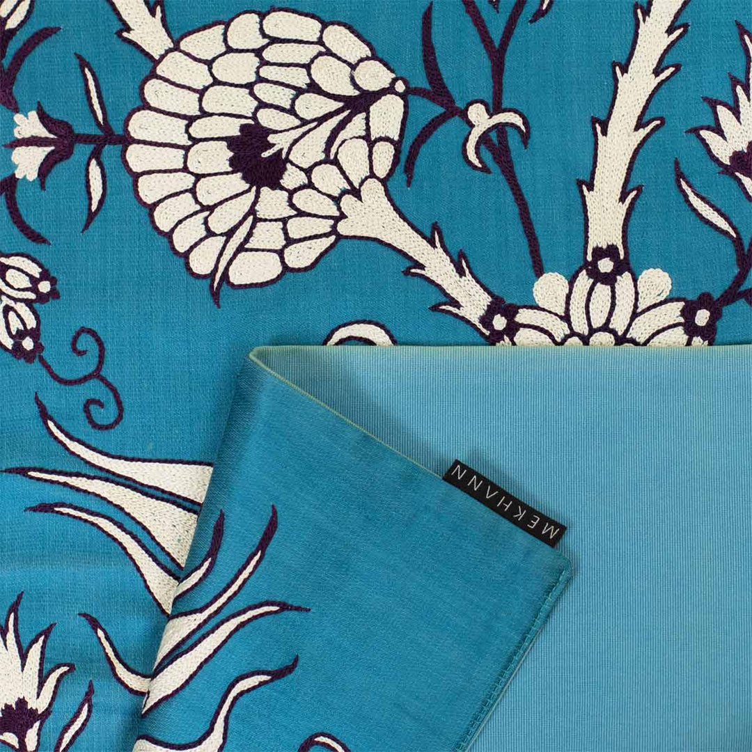 Folded view of Mekhann's pomegranate vines runner, howing the back lining of the turquoise runner alongside the Mekhann label.