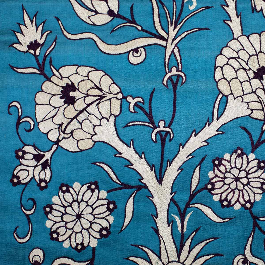 Detailed view of Mekhann's pomegranate vines runner, Detailed embroidery of the turquoise runner, featuring white pomegranate vines that provide a contrast against the vivid background.