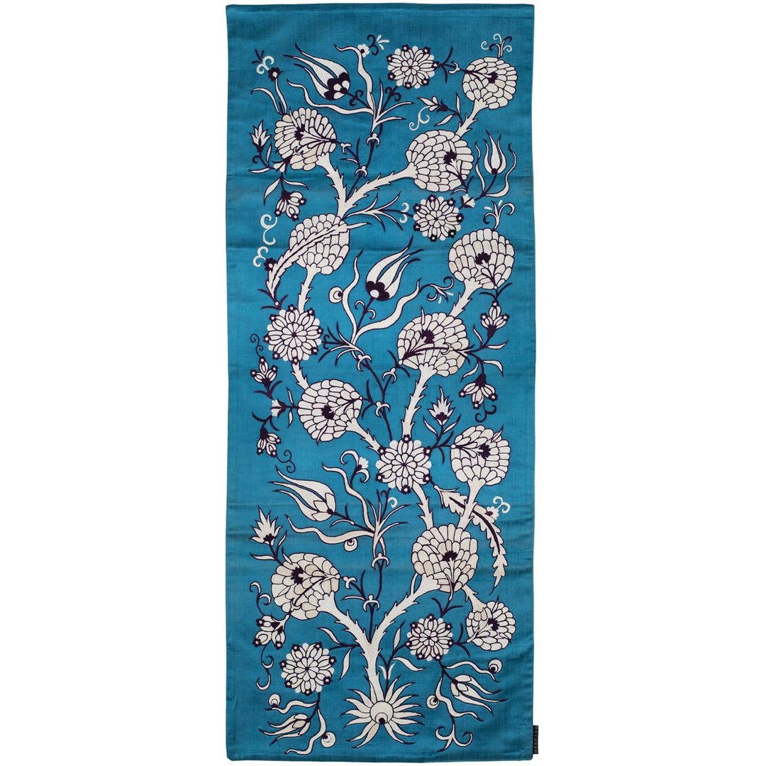 Front view of Mekhann's pomegranate vines runner, an elegant turquoise coloured runner with pomegranate vines embroidery in cream and black, all details have been hand embroidered onto a silk turquoise base fabric.