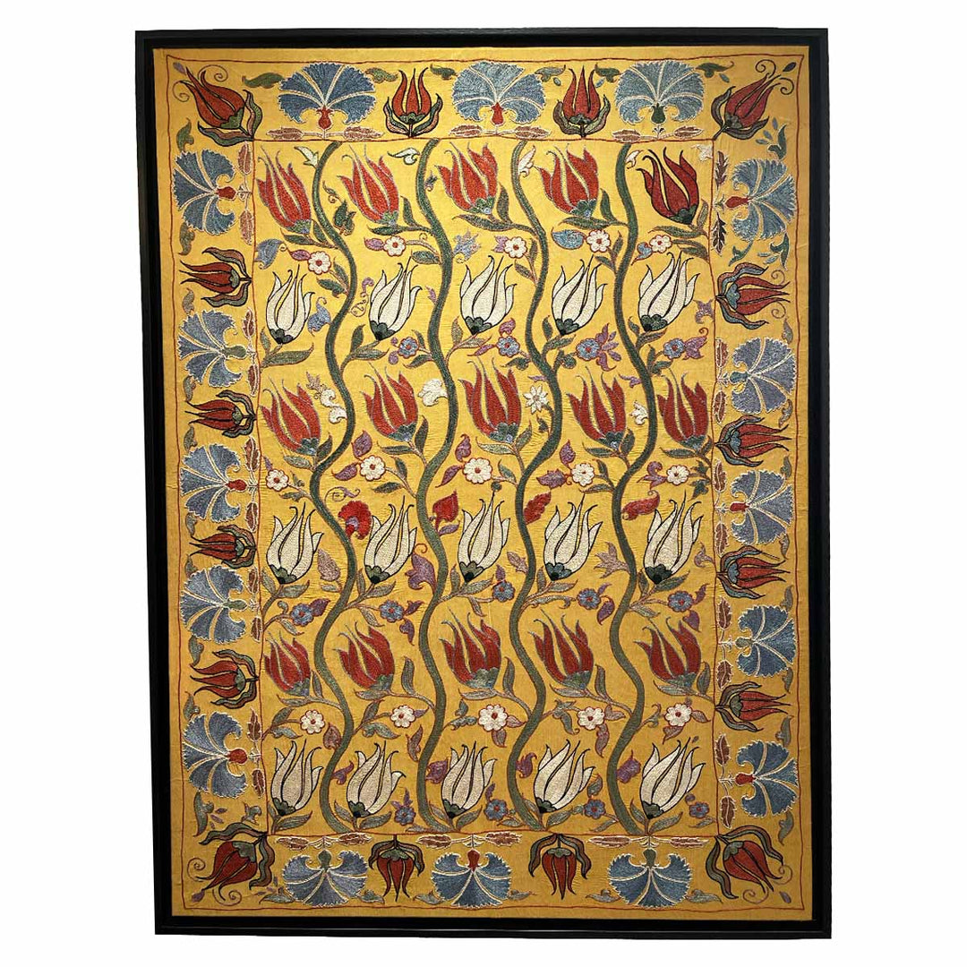 A framed artwork featuring a botanical pattern with tulip designs in red, yellow, and blue on a beige background.